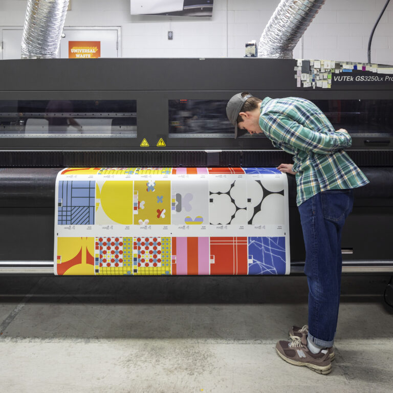 Image of a person inspecting samples coming off of a printer.